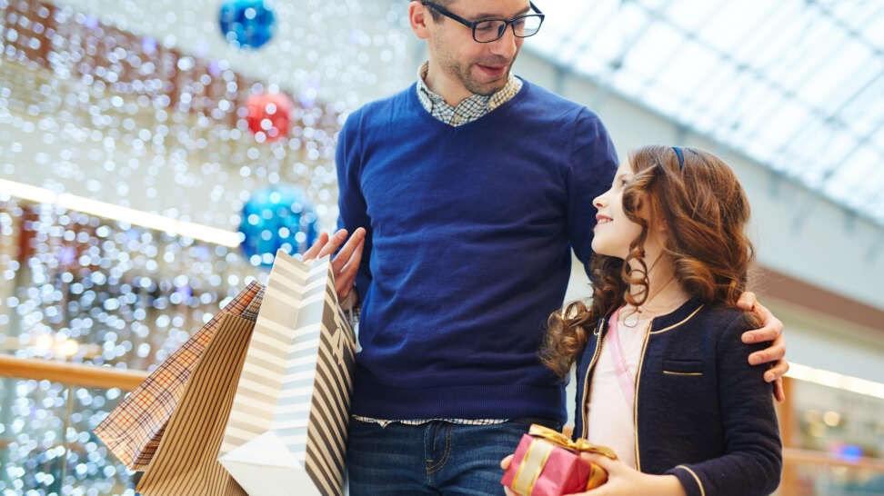 Hombre paseando por shopping comprando regalos con su niña